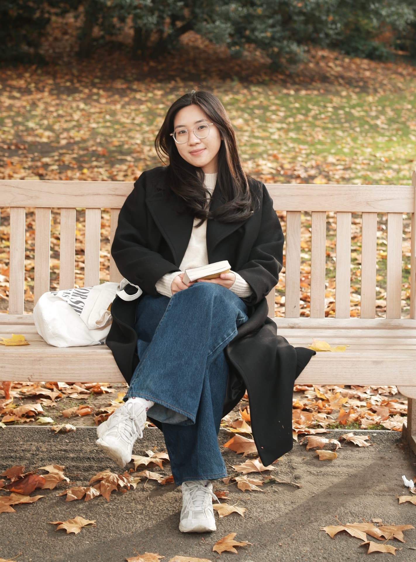 Tra sitting on a park bench with a book